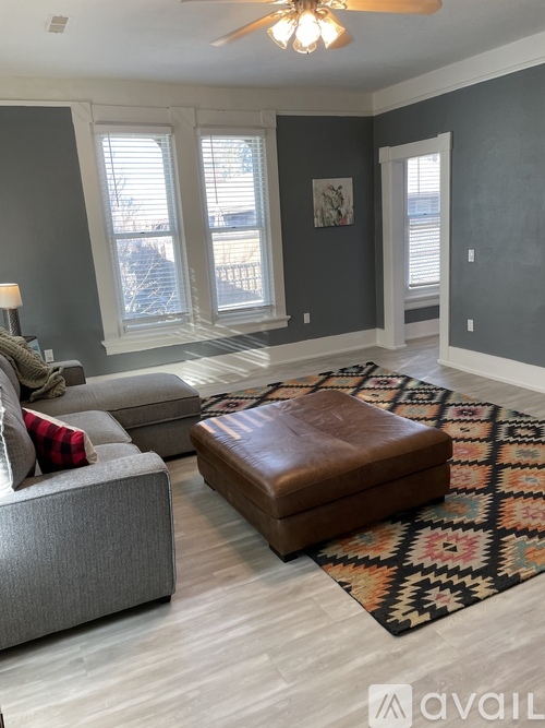 A living room with a grey couch and a brown ottoman.