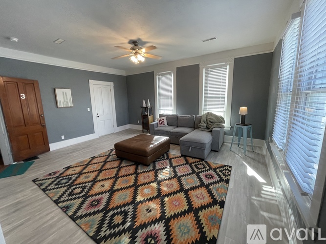 A living room with a rug, a couch, and a ceiling fan.