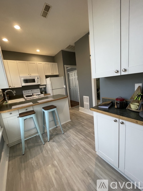 A kitchen with white cabinets and a black countertop.