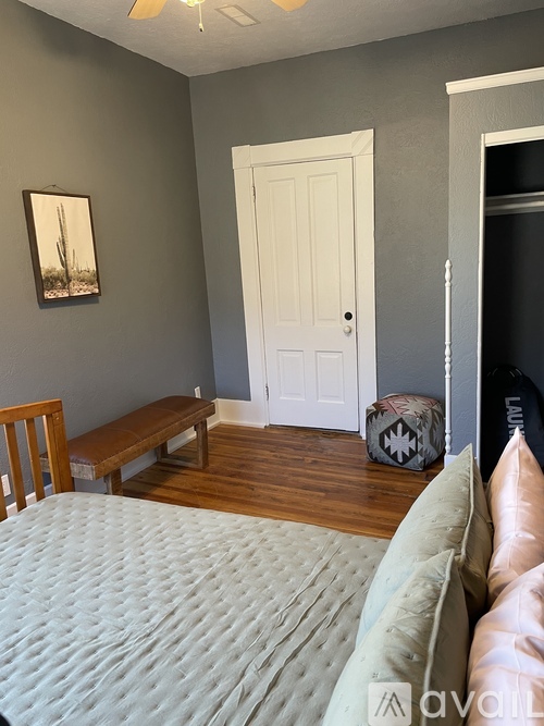 A bedroom with a bed, a bench, and a painting on the wall.