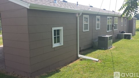 A house with a grey siding and a white window is available for rent.