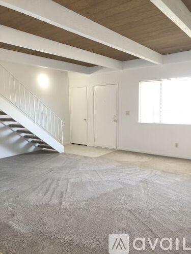 A room with a carpeted floor and a staircase leading to another room.