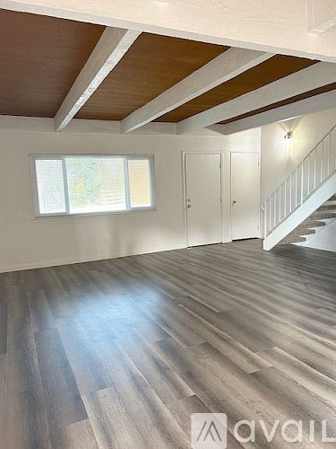 A room with a carpeted floor and a staircase leading to another room.