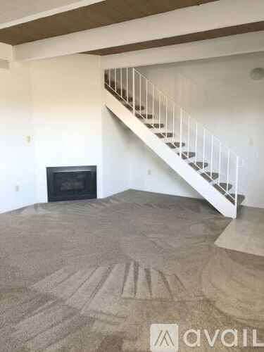 A living room with a fireplace and a staircase.