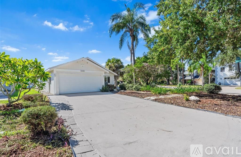 A house with a driveway and trees in front of it.