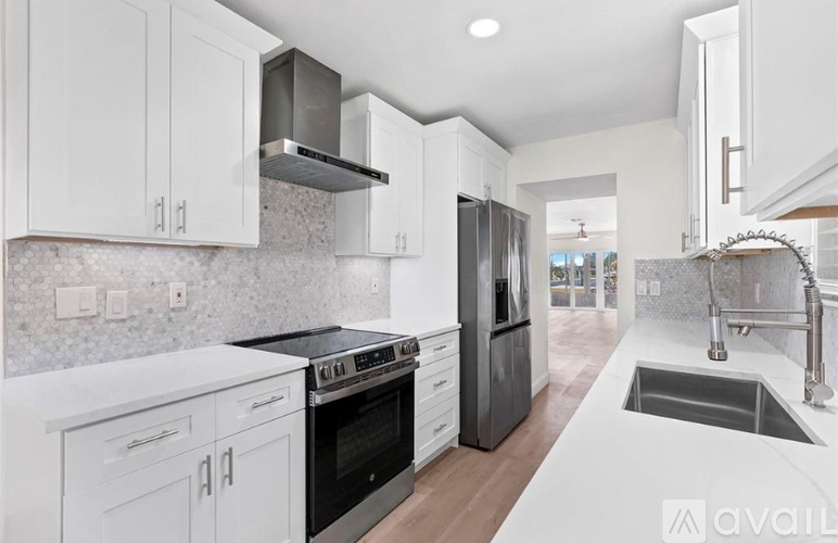 A modern kitchen with white cabinets and stainless steel appliances.
