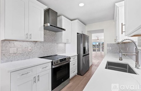 A modern kitchen with white cabinets and stainless steel appliances.
