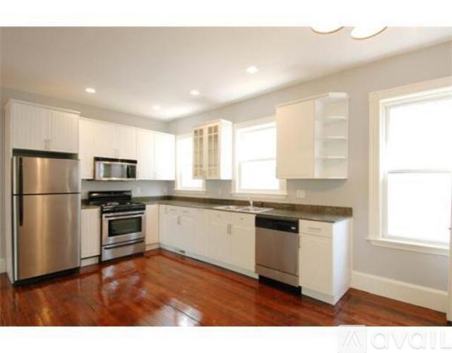 A kitchen with white cabinets and a wooden floor.