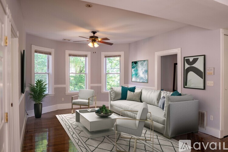 A living room with a white couch and a rug.