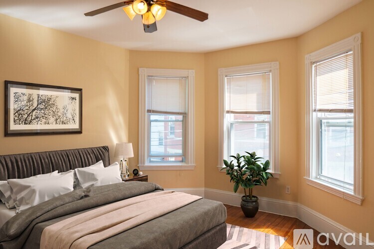 A bedroom with a bed, a ceiling fan, and a potted plant.