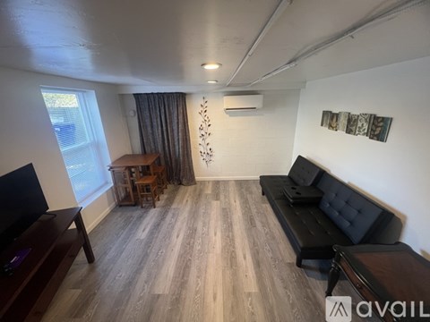 A living room with a black couch and wooden floors.