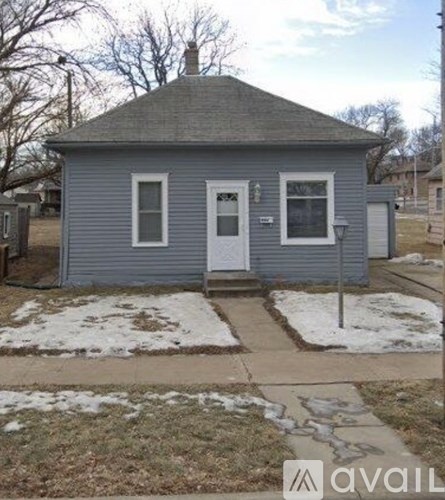 A small house with a white door and a grey roof.
