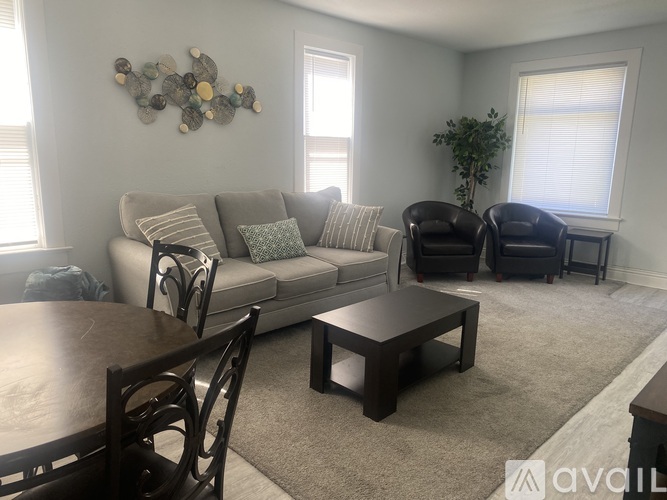 A living room with a couch, chairs, and a table.