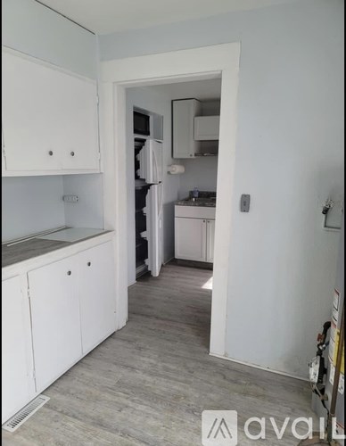 A kitchen with white cabinets and a view into the adjoining room.