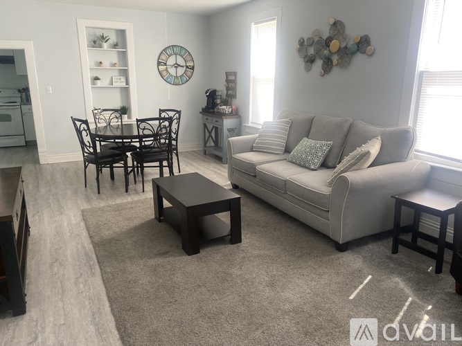 A living room with a grey couch, a coffee table, and a dining table with chairs.