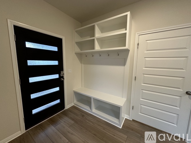 A white built-in shelf unit in a room with a black door.