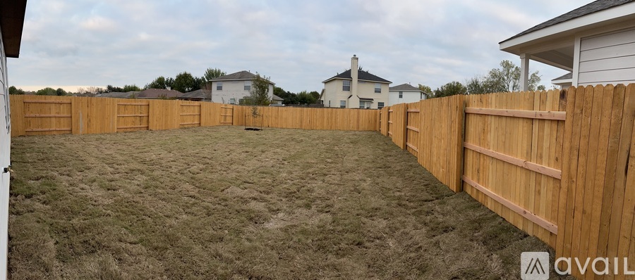 A backyard with a wooden fence and a grassy area.