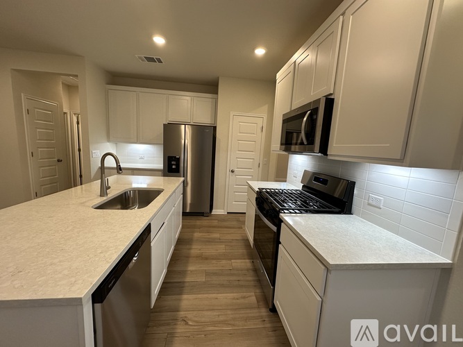 A kitchen with white cabinets and a stainless steel refrigerator.