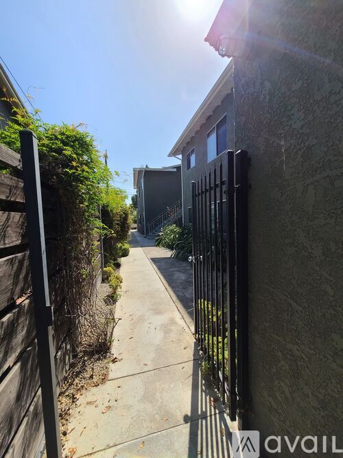 A narrow alley with a black gate and a building on the right.