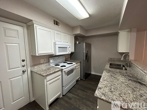 A kitchen with white cabinets and granite countertops.