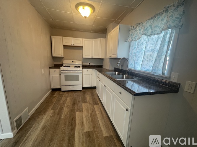 A kitchen with white cabinets and a wooden floor.