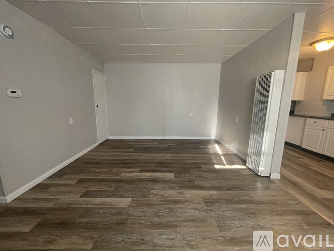 A room with wooden flooring and white walls, with a white door and a white cabinet.