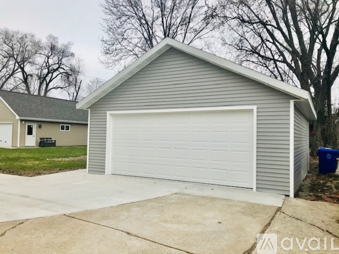 A two-car garage with a white door is attached to a house.