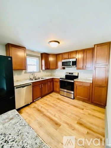 A kitchen with wooden cabinets and a black refrigerator.