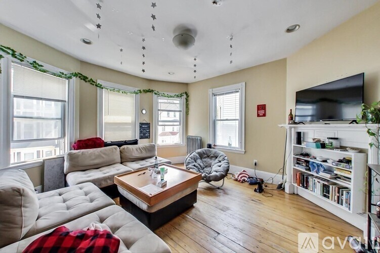 A living room with a grey couch, a wooden coffee table, and a television on the wall.