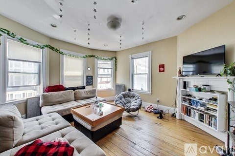 A living room with a grey couch, a wooden coffee table, and a television on the wall.