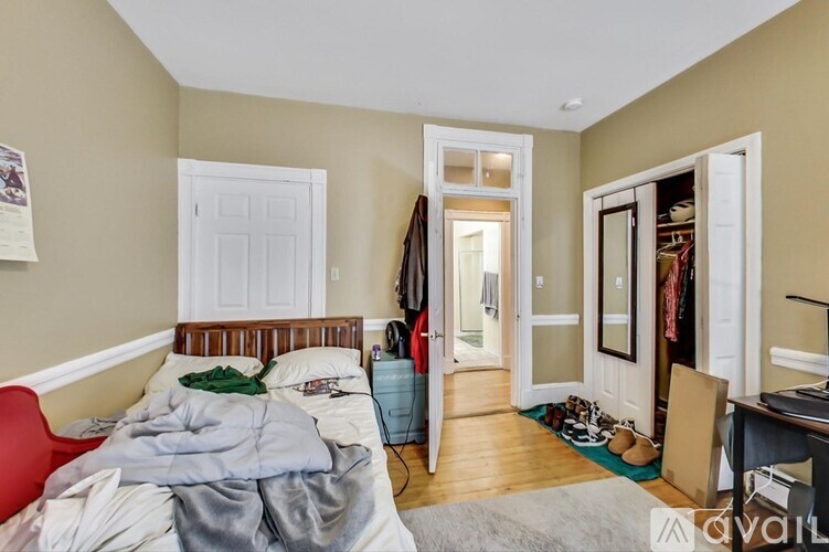 A bedroom with a bed, a desk, and a closet.