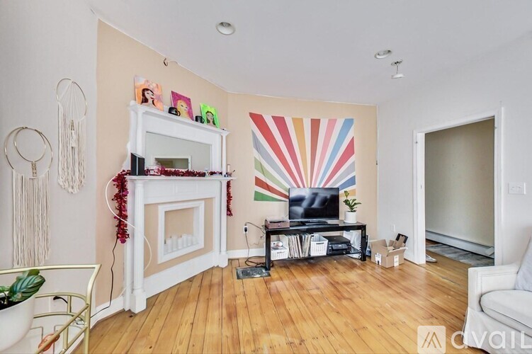 A living room with a fireplace and a colorful sunburst painting on the wall.