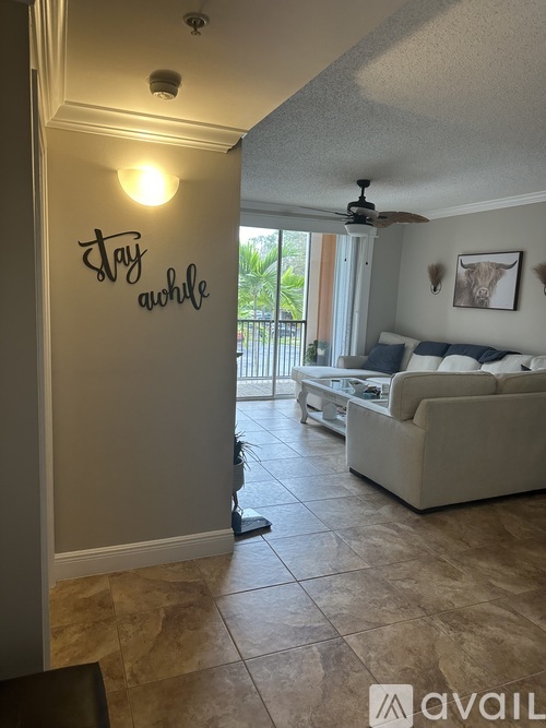 A living room with a couch and a wall with the words "Stay Awhile" written on it.