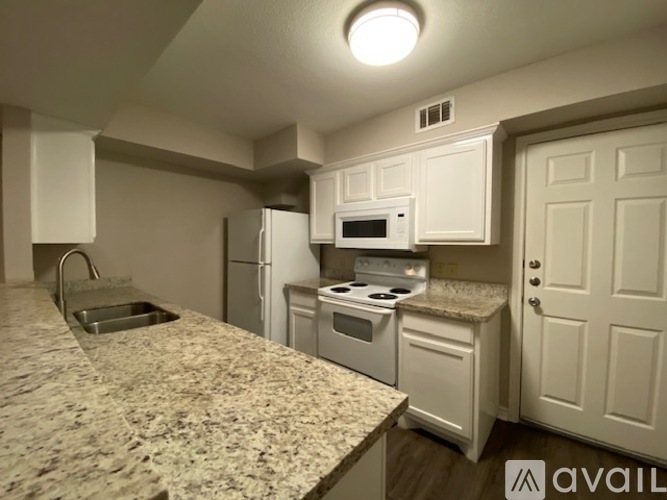 A kitchen with granite countertops and white appliances.
