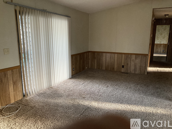 A room with a carpeted floor and a window with blinds.