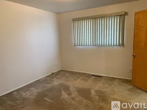 A room with a window covered by blinds and a wooden door.