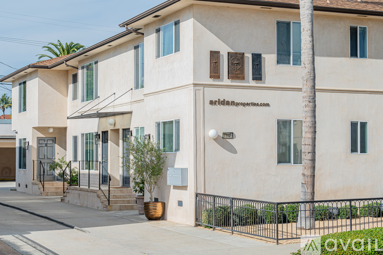 A beige two-story house with a black fence in front.