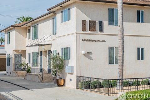 A beige two-story house with a black fence in front.