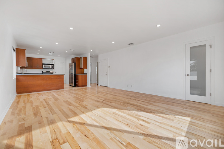A spacious room with wooden flooring and white walls.