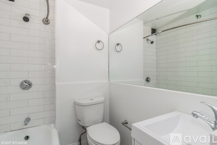 A white bathroom with a toilet, sink, and shower.