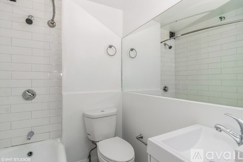 A white bathroom with a toilet, sink, and shower.