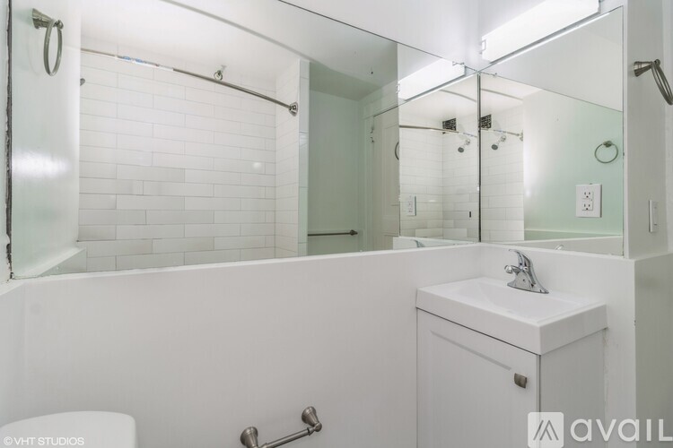 A white bathroom with a toilet, sink, and shower.