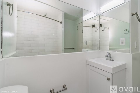 A white bathroom with a toilet, sink, and shower.