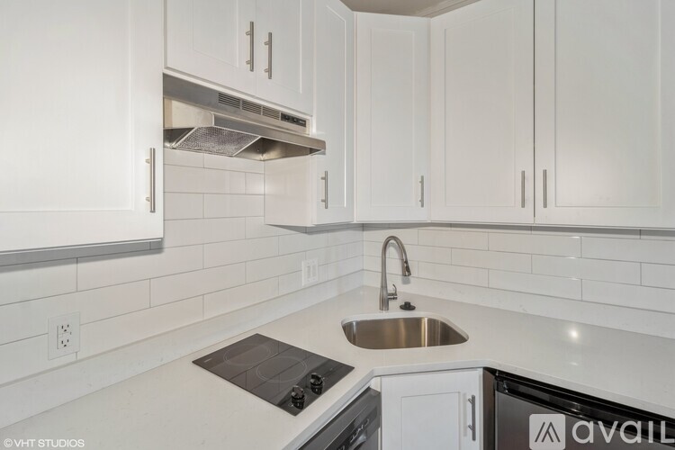 A kitchen with white cabinets and a stove top oven.