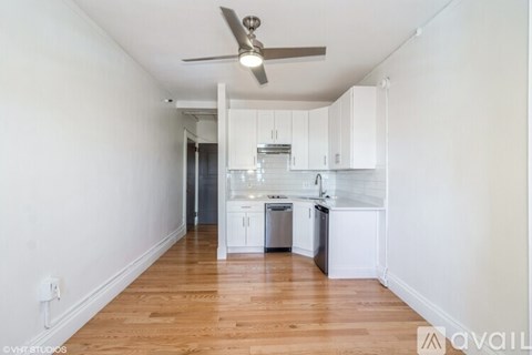 A kitchen with white cabinets and a wooden floor.