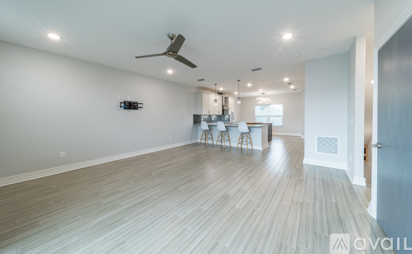 A spacious room with a ceiling fan and a dining area with chairs.