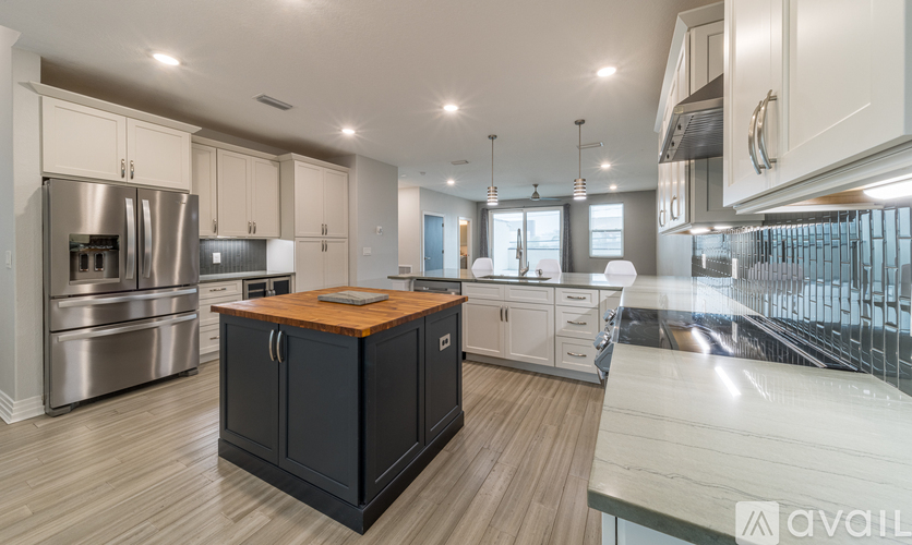 A modern kitchen with a wooden island in the center.