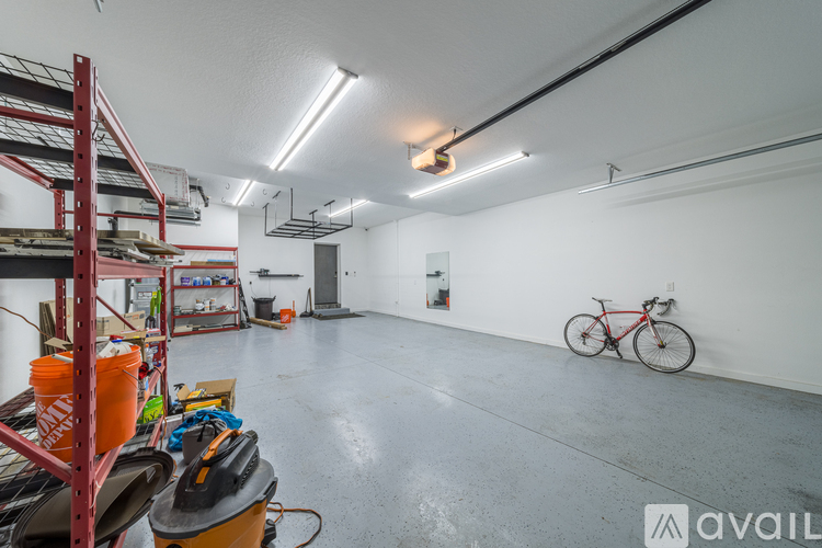 A spacious garage with a bicycle and a shelf with various items.