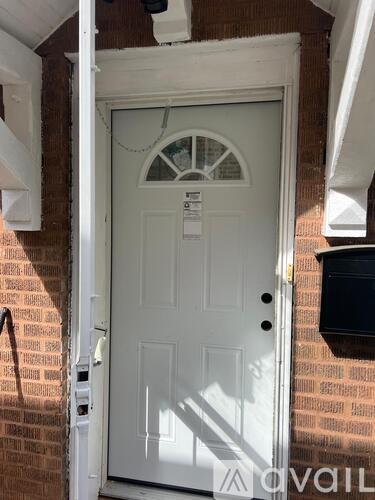 A white door with a glass window in the middle and a mailbox on the right.