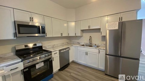 A kitchen with white cabinets and stainless steel appliances is available for rent.
